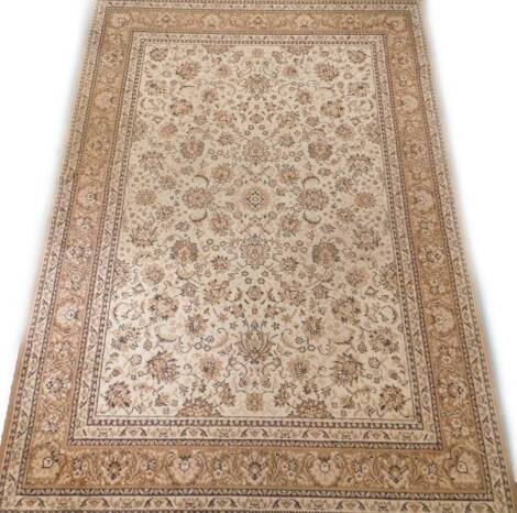 A machine woven rug, decorated with an oriental style design in beige and cream, 240cm x 170cm.