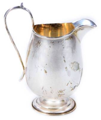 A George V silver cream jug, with thumb mould handle, beak spout, plain bulbous body, on squat stem and stepped circular foot, Birmingham 1914, 12cm H, 3oz.