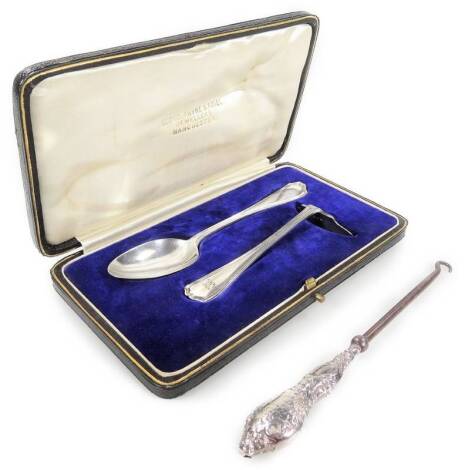 A George V silver Christening set, comprising medicine spoon 15cm W and pusher, each with shaped handles, (cased), and a silver handle button hook with plain metal end.