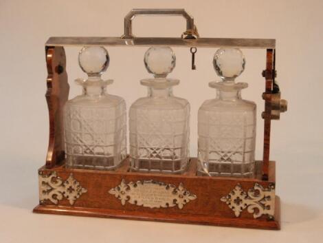 An Edwardian oak and electroplate three bottled Tantalus (decanters AF)