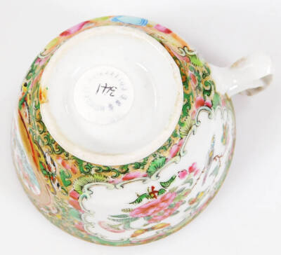 A 19thC Cantonese porcelain tea cup, with shaped handle, the circular bowl decorated with panels of figures in an interior setting, broken by further panels and flowerheads, in famille rose colours, predominately in pink, green, yellow and blue, on a circ - 6