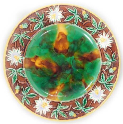 A 19thC majolica floral pottery plate, of circular form raised with mayapple flowers and leaves, the inner with a tortoiseshell decoration, predominately in green, orange and brown, unmarked, 25cm Dia.