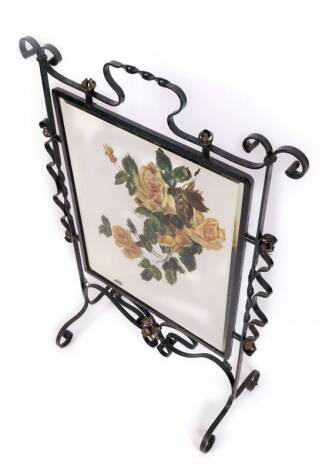 A wrought iron framed firescreen, in black with central mirror, partially painted with roses, with a central twist handle, on scroll legs, 91cm H, 56cm W, 27cm D.