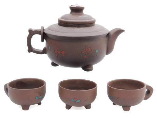 A Chinese redware pottery part service, comprising of a teapot with compressed circular lid, 14cm H, sparsely decorated with flowers predominately in blue and red, with a ring and ear handle, on compressed feet, seal mark beneath, and three similar cups,