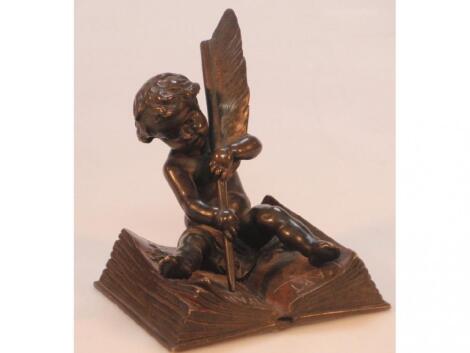 A 19thC French bronze figure of a seated putti with a feather pen