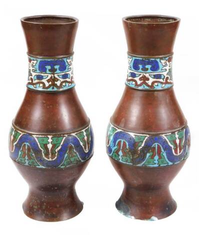 A pair of champleve enamel bronzed metal vases, each of bulbous form with an upper and lower geometric banding predominately in blue and green, on circular feet, unmarked, 31cm H. (2)