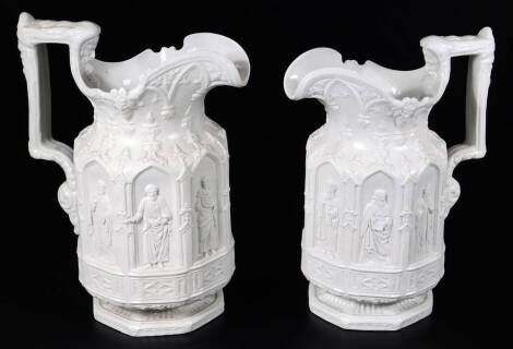 A pair of 19thC Charles Keige ecclesiastical jugs, each in cream with panels raised with figures and shaped thumb mould handles, on octagonal bases, raised purple marks beneath, 23cm H. (2)