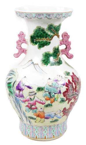 A Chinese porcelain famille rose baluster vase, with compressed trumpet stem, shaped handles and bulbous body, heavily decorated with children playing blind man’s buff, with mountains and trees in the distance, predominately in pink, purple and green, on