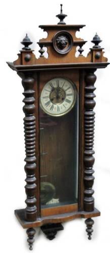 A 19thC walnut Vienna wall clock, the 17cm Dia. Roman numeric dial fronting an eight day keywind movement, in a three part glazed case, flanked by quarter columns and surmounted by a lion’s mask patera, with urn finials, pendulum and single weight, 124cm