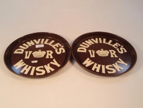 A pair of brown tin circular pub trays enamelled in cream advertising Dunstilles Whisky