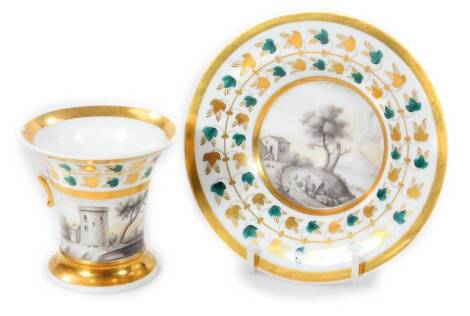 A 19thC porcelain cup and saucer, polychrome decorated with gilt highlights, with a black and white scene of figures, trees and buildings, (cup, 7cm H, AF)