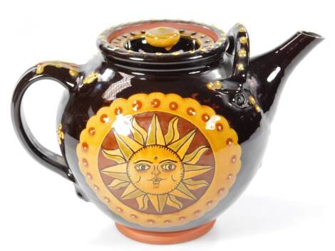 20thC slip ware teapot, decorated with a sun to either side, on a brown ground, 21cm H.