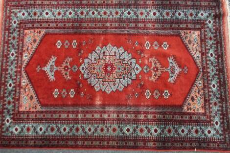 A Middle Eastern rug, in a repeat floral pattern predominately in red and light blue with yellow highlights, 127cm W.