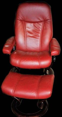 A 20thC swivel chair and foot stool in red leather, 50cm W.