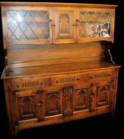 A 20thC Old Charm style dresser, the upper section with led glazed panel doors centred by a cupboard above, three frieze drawers and cupboards beneath, on a block style, 163cm H, 147cm W, 43cm D.