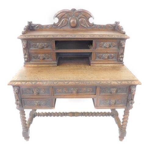 A Victorian oak desk, the upper super structure having a galleried top, carved with scrolling leaves and flowers, over four short drawers with carved lion mask handles and scrolling decoration, over one medium and four short drawers, similarly carved, rai