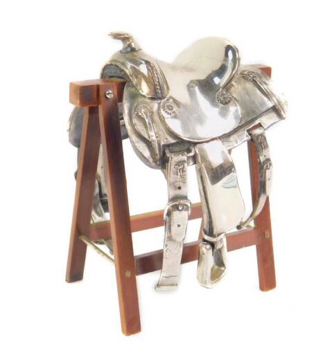 A Sacchetti silver model of a horse saddle, with skirt, flanks, stirrups and fenders, signed, stamped 925, raised on a wooden trestle, 9.5cm H.