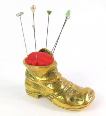 A brass pin cushion modelled as a shoe, containing six hat pins.