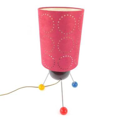 A retro atomic table lamp, with tyrolite bowl body, raised on three metal legs and vari-coloured ball feet, with a pierced cylindrical red suede shade, 52cm H.