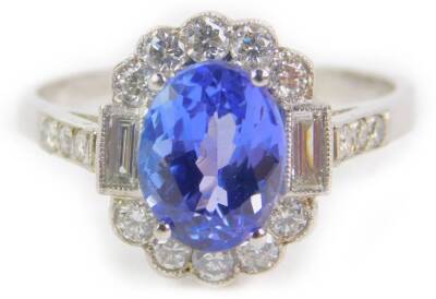 A tanzanite diamond and platinum ring, the oval cut tanzanite in a surround of brilliant and emerald cut diamonds, with diamond set shoulder, tanzanite approx 1.2cts, size P, 5.5g.