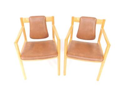 A pair of Ercol beech carver chairs, with brown rexine headrest and overstuffed seat, raised on turned legs.