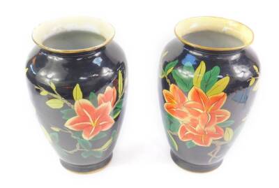 A pair of Chinese porcelain vases, later over painted with flowers against a black ground, 30cm H. (AF)