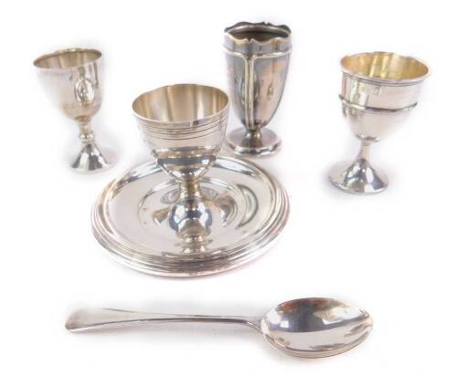 A George VI silver egg cup, on an integral base, London 1946, George V silver egg cup, Birmingham 1915, spoon and two further egg cups, 5.94oz all in.