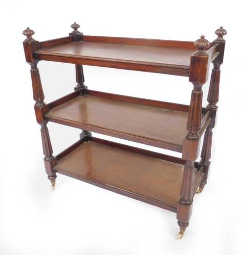 A Victorian mahogany three tier buffet, with a three sided galleried top, raised on fluted and turned supports, brass capped on castors, 97cm H, 89cm W, 42cm D.