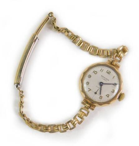 An Excaliber 9ct gold circular cased lady’s wristwatch, silvered dial bearing Arabic numerals, subsidiary seconds dial, on a plated strap, 14.1g all in.