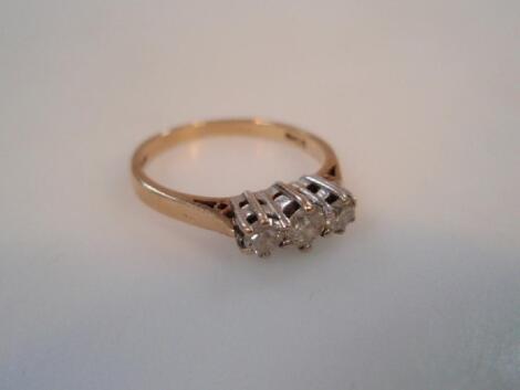 A diamond three stone dress ring in a yellow metal mount