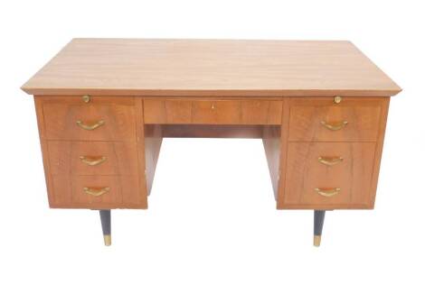 A Sellex veneered office desk, c1960s/70s, with one long drawer flanked by filing and other drawers, raised on turned ebonised legs, brass capped, 77cm H, 137cm W, 76cm D.