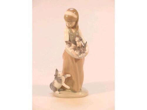 A Lladro figure of a young girl holding three kittens in her arms