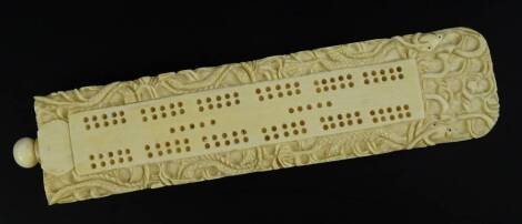 A late 19thC Chinese Canton carved ivory cribbage scorer, of wedge shape, decorated with stylised dragon etc., the screwed finial containing various markers, 16cm L.