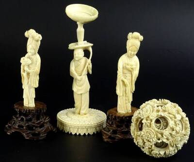 A group of late 19th/early 20thC Chinese ivories, to include a pair of female figures, one carrying a flower the other a cup and saucer, on a pierced carved hardwood base, and a concentric ball with figural stand, the figures, 16cm H overall, the concentr