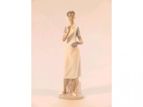 A Lladro figure of a nurse holding a clipboard and a pen