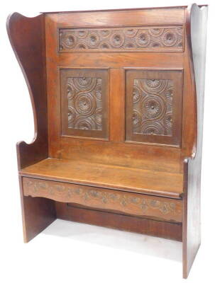 An early 20thC oak settle with a carved panelled back shaped sides and double seat, 107cm W.