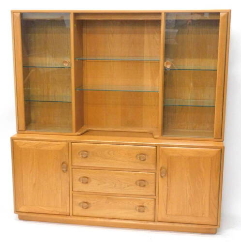 An Ercol blonde elm dresser, the raised back with two glazed doors enclosing adjustable glass shelves, flanking a central recess, the sideboard base with three drawers and two doors on castors, 155cm W.