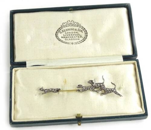 A diamond set fox and hound brooch, depicting a fox being chased by three hounds, each animal set with tiny diamonds to the body and a ruby to the eye, in white metal setting, unmarked, on a yellow metal bar brooch, 7cm W, in a G.Kenning & Son, London, Li