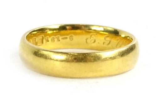 A 22ct gold wedding band, of plain design with engraving to inner band E.G.W-L.B 15-7-22, maker B and Co, 5g.