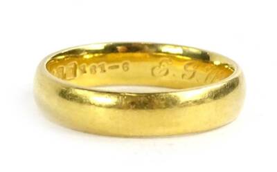 A 22ct gold wedding band, of plain design with engraving to inner band E.G.W-L.B 15-7-22, maker B and Co, 5g.