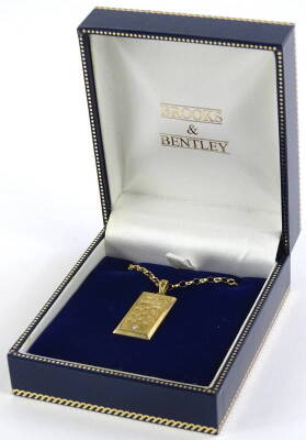 A Brooks and Bentley 9ct gold ingot pendant and chain, the pendant set with crown and three lions and tiny white stone to bottom, on a curb link 9ct gold chain, 9.1g all in.