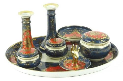 A Noritake porcelain dressing table set, decorated in Imari colours, picked out in gilt, to include a pair of candlesticks, ring holder, covered jars, a bowl and an oval tray, the tray 32cm W.