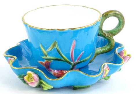 A Victorian turquoise glazed oriental style cup and saucer, decorated with shells, serpents, flowers etc., possibly Minton, (AF), the saucer 14cm W.