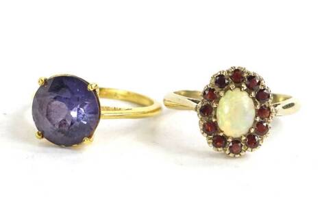 Two dress rings, to include a 9ct gold floral cluster ring, with central opal surrounded by garnets, 2.4g, and a gold plated paste stone set dress ring. (2)