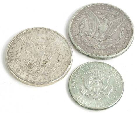 Three American coins, an 1883 silver dollar, 1902 silver dollar and a half dollar.