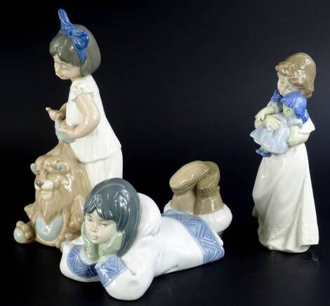 A Nao porcelain figure of an Eskimo girl lying down, boxed, and a figure of a girl with a doll, and a figure of a girl with a toy lion. (3) Auctioneer Announce: Figure girl with toy lion - glue become dried & head no longer attached