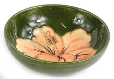 A Moorcroft pottery bowl, decorated with a peach coloured flower, on a green ground, impressed mark to underside, 11.5cm diameter.