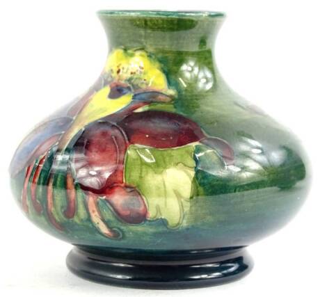 A Moorcroft pottery squat vase, decorated with pansies, on a green ground, 8cm W.