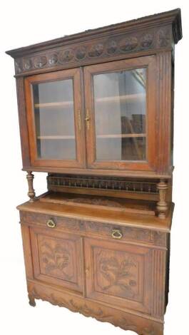 A French carved oak buffet, the top with two glazed doors, on turned supports, the base with two frieze drawers above two panelled doors on shaped feet, 125cm W.