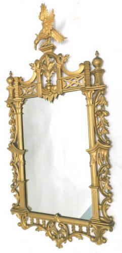 A giltwood and gesso wall mirror, in the style of Thomas Johnson, the crest decorated with an eagle, above a pierced floral and C 'scroll' decoration, 158cm x 73cm.